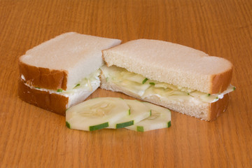 A cucumber sandwich with mayo on a wood background.