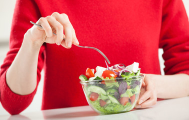 Unrecognizable young woman eating fresh salad