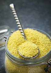 Uncooked couscous in a glass jar, selective focus