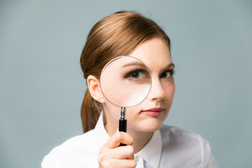 Young woman looking through a magnifying glass. 