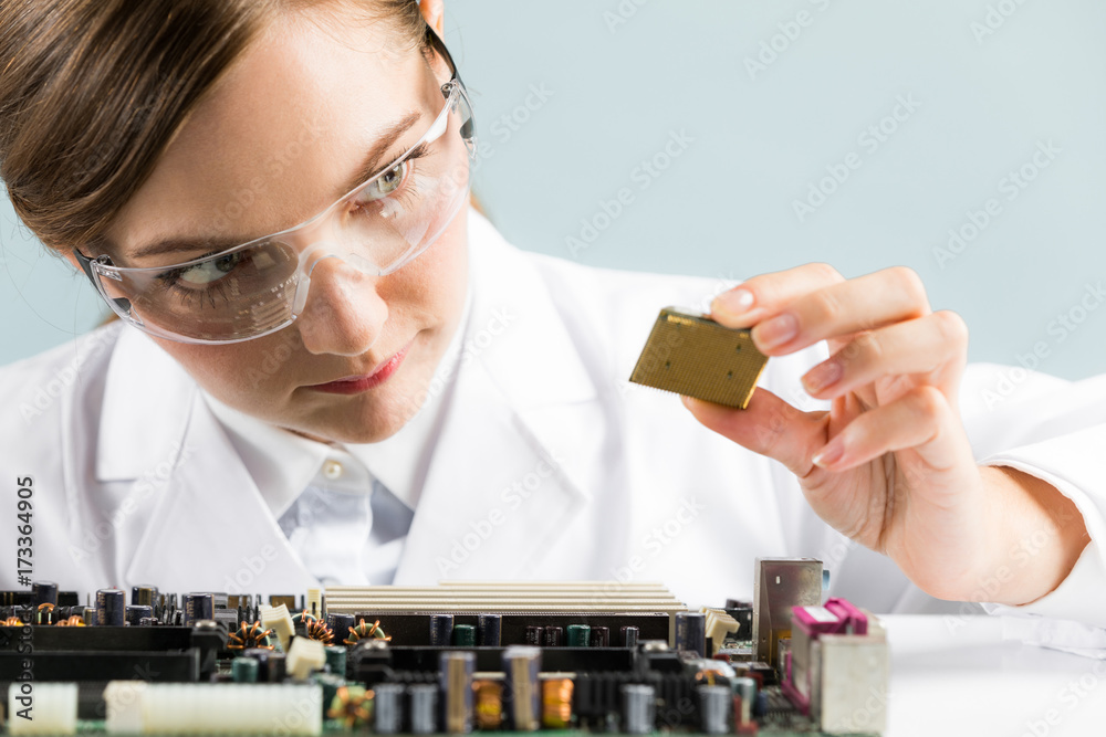 Wall mural Electronics technology concept. Young woman engineer holding computer chip.