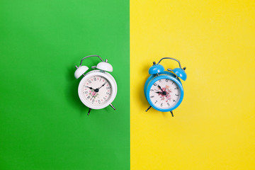 Flat lay retro beautiful new alarm clock on green and yellow paper pastel color background.