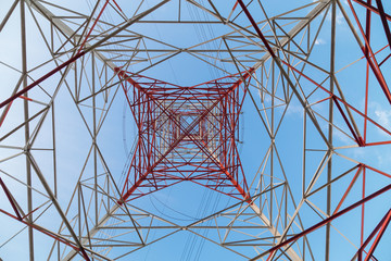 Perspective view under a huge red electricity supply pylon