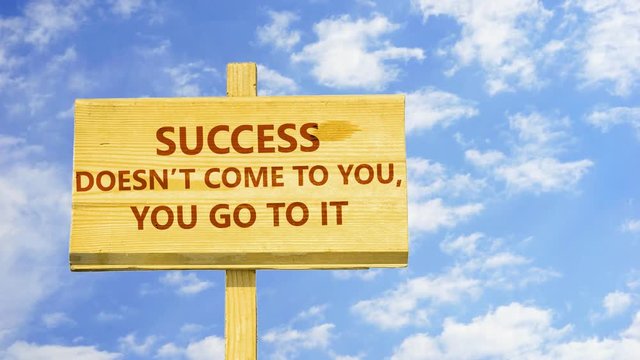 Success doesn't come to you, yo go to it. Words on a wooden sign against time lapse clouds in the blue sky.