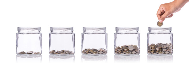 Hand holding Thai coin (baht) and insert to clear glass jar. Studio shot isolated on white. Save money or investment financial for future concept