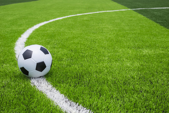 Soccer ball on artificial bright and dark green grass at public outdoor football or futsal stadium