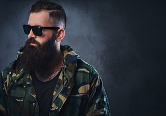 A man dressed in a camouflage jacket over grey background.