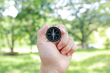 Compass in hand against nature background.