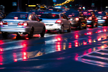 blurry image of city traffic during evening rush hour on wet road