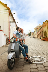 happy young couple riding scooter in town. Handsome guy and young woman travel. Adventure and vacations concept.