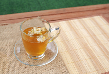 Chrysanthemum juice in glass cup and dried Chrysanthemum flower on wood background.