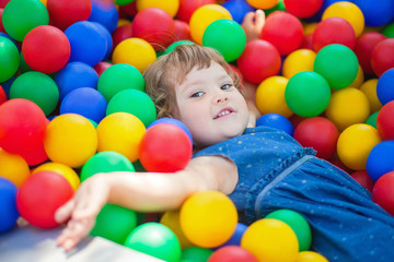 Fototapeta na wymiar Happy little girl child in colourful plastic balls pool.