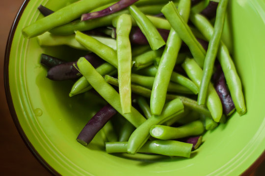 Raw multicolored green and purple beans close up on a plate.
