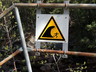Warning sign about descent of water on  bank of canyon of Imatrankoski waterfall. Imatra, Finland