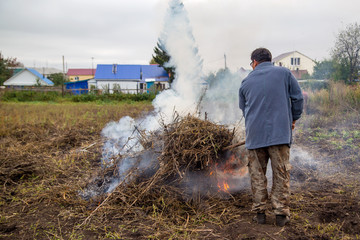 a farmer with grass on the forks to burn the weeds in the garden