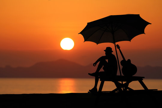 Silhouette of a man playing a guitar on the beach