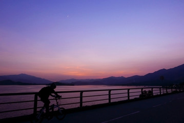 Silhouette of bicycle, fence, mountain, gradient purple sky