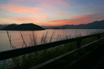 Silhouette of mountain, fence and ocean at sunset