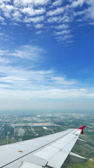 Fototapeta na wymiar Wing of airplane, green land and blue sky