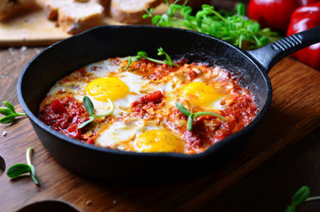 Shakshuka, Fried Eggs with Tomato Sauce in a Pan, Rustic Style and Wooden Background