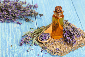 Herbal oil and lavender flowers on wooden background