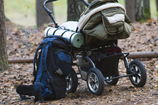 Baby stroller and camping backpack in autumn forest