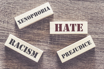 Hate, xenophobia, racism and prejudice words written with tiles on a wooden table. Social issues concept - obrazy, fototapety, plakaty