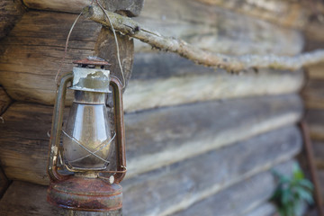 An old kerosene lamp hanging on the background of a log wall