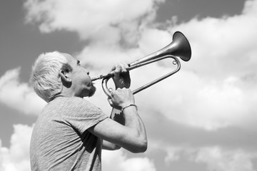 Man playing trumpet on sky background