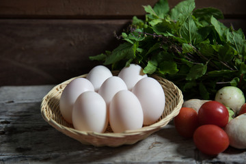 White egg in bamboo basket on wooden table