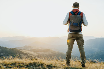 Hiker with backpack standing and looking at mountain