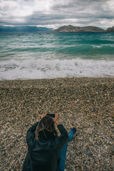Woman taking photographs on the beach