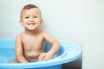 Naklejka premium Happy child boy swims in the bathtub