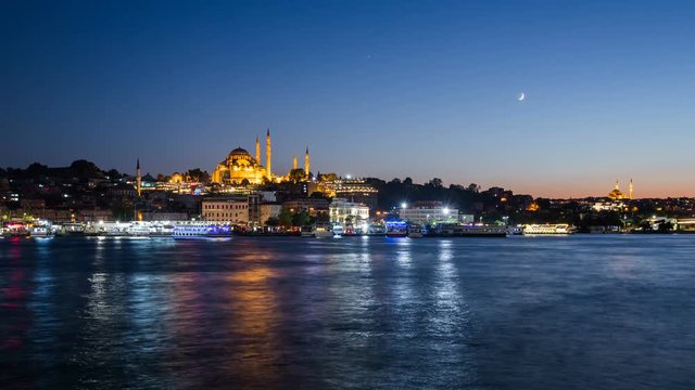 Zoom out Timelapse view of Istanbul cityscape with Suleymaniye mosque with tourist ships floating at Bosphorus at night
