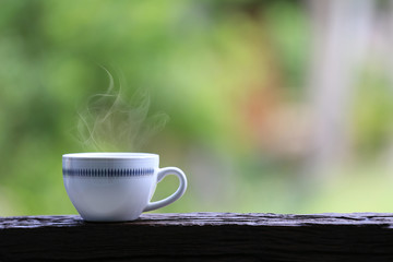 White coffee mug on wooden floor and green nature background.