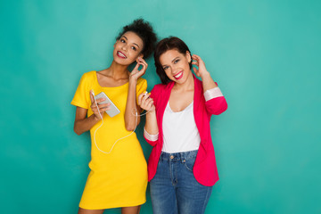 Happy female friends listen to music at studio background