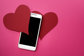 Hearts and smartphone. The concept to like in social networks or Dating app. pink background