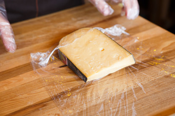 Shop assistant wrapping a piece of cheese
