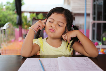 Asian child girl use Pencil write letters on the book.