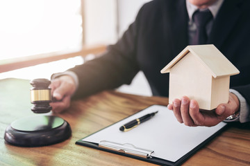 Male lawyer or judge hand's striking the gavel on sounding block, working at courtroom for decide home insurance, Law and justice concept, Settle a house dealing lawsuit