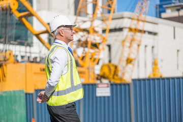 Senior foreman in glasses doing his job at building area on sunny day