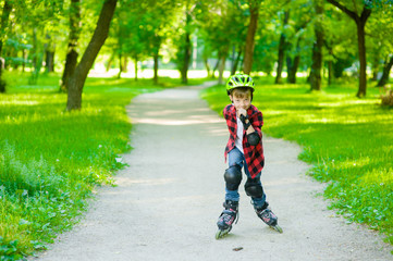 Fototapeta premium Young boy learn to roller skate in summer park. Space for text.