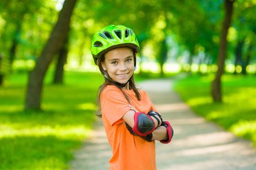 Fototapeta na wymiar Portrait of a girl with arms crossed in a protective helmet and protective pads for roller skating