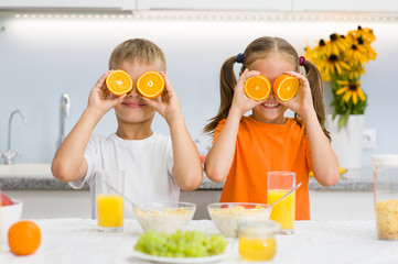 Happy kids holds orange before his eyes like in glasses