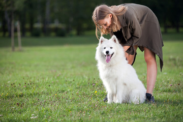 Pretty young girl with her samoyed dog at the park