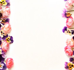 Floral frame made from colored violets and pink roses on a white background