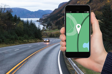 Hand with phone on a background of a road. Navigation concept