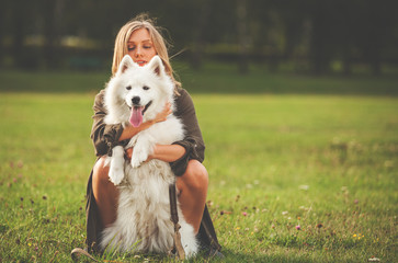 Naklejka na ściany i meble Pretty girl playing with her dog in the park, samoyed