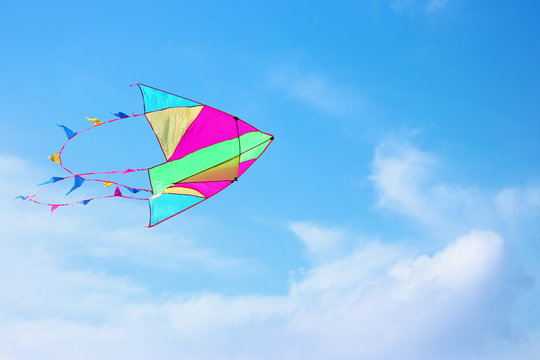 Colorful kite flying in the blue sky through the clouds