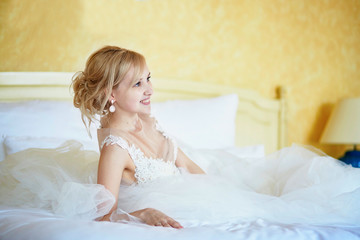 Obraz na płótnie Canvas Cheerful young bride in wedding dress in hotel room